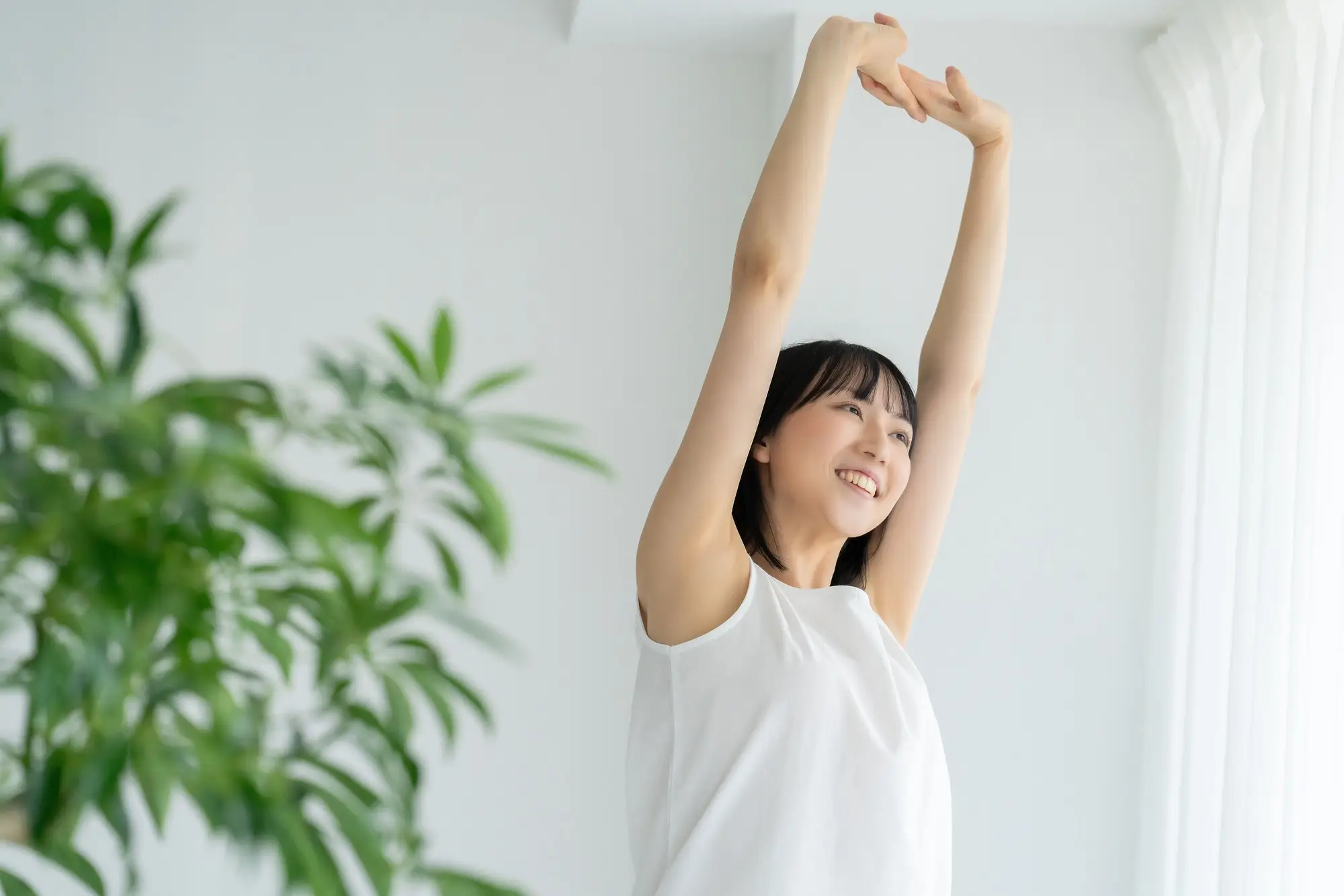 腕を上に上げて伸びをしている女性の画像